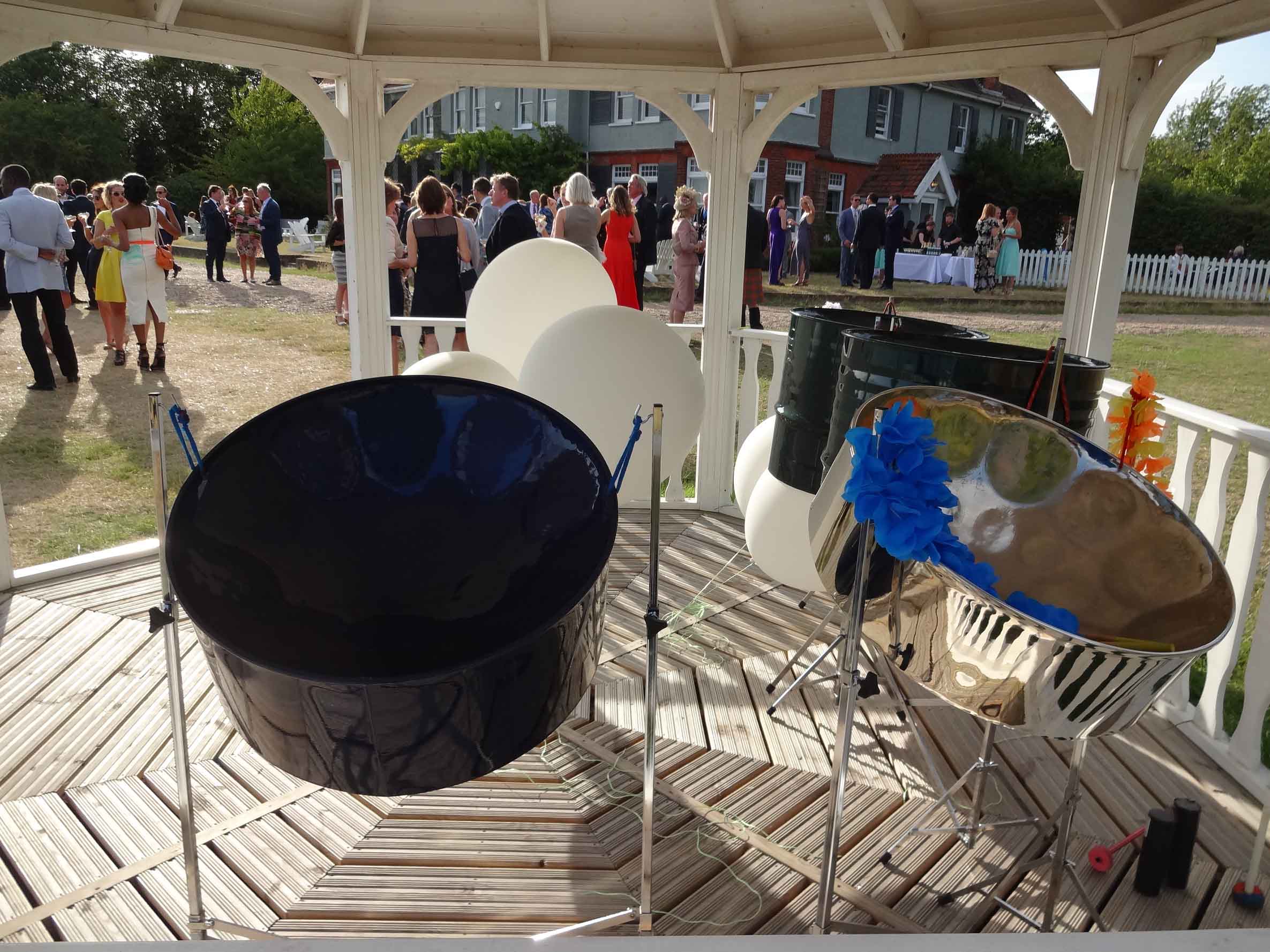 Caribbean steel drum band set up at a wedding on Osea Island, with guests enjoying drinks and celebrating in a picturesque venue.